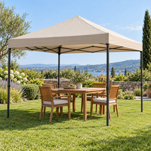 Tonnelle pliante de jardin avec un toit beige neuf bien tendu au-dessus d'une table et de quatre chaises, pelouse verte, ciel clair