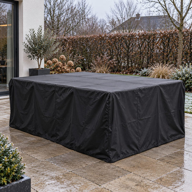 Table de jardin et chaises entièrement couvertes d’une housse noire qui tombe jusqu’au sol, sur une terrasse propre en hiver
