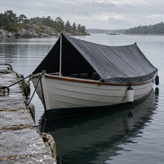 Petit bateau de pêche sous un taud sombre bien tendu en forme de toit sur deux poteaux, amarré à un quai en pierre après la pluie