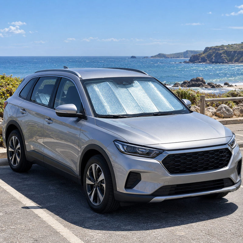Voiture garée sur un parking de bord de mer avec un pare-soleil argenté derrière le pare-brise et un second pare-soleil plié sur la banquette