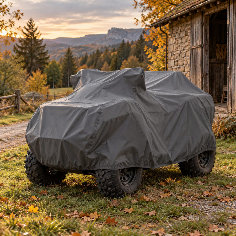 Quad tout-terrain couvert d'une housse grise robuste près d'une grange